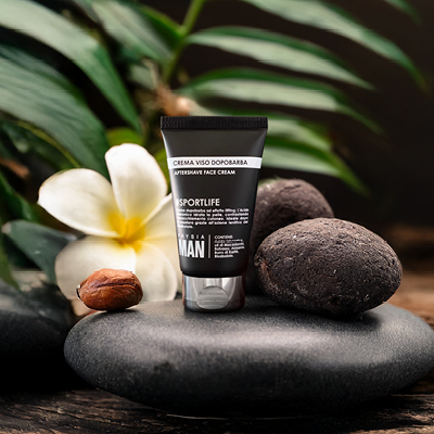 immagine del prodotto Crema Viso dopo barba su sfondo nero con foglie, fiori bianchi e sassi neri 